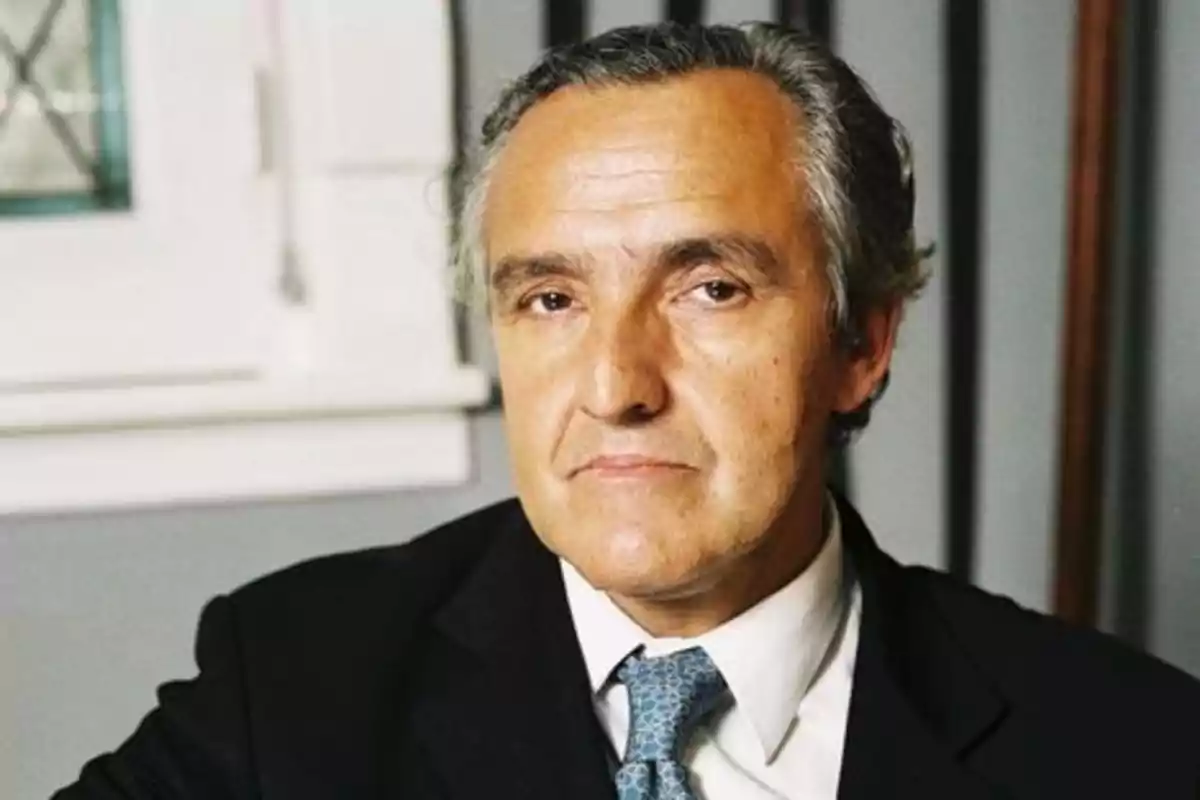 Un hombre de cabello canoso y traje oscuro mira a la cámara con expresión seria. Un hombre de cabello canoso y traje oscuro mira a la cámara con expresión seria.
