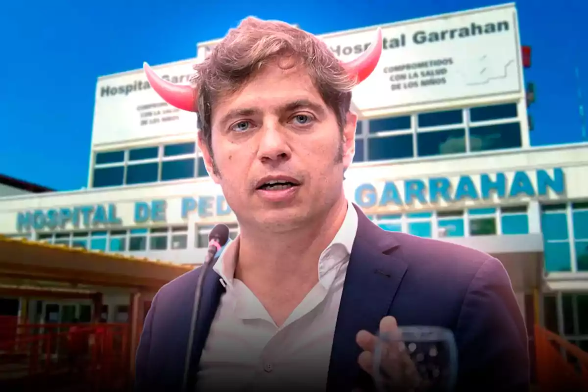 A man in a suit with red horns on his head is speaking in front of the Garrahan Hospital.