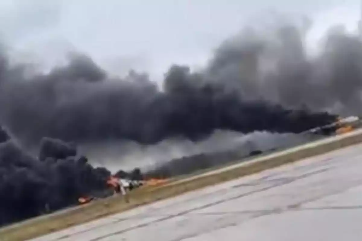 Densa columna de humo negro y llamas en una pista de aterrizaje