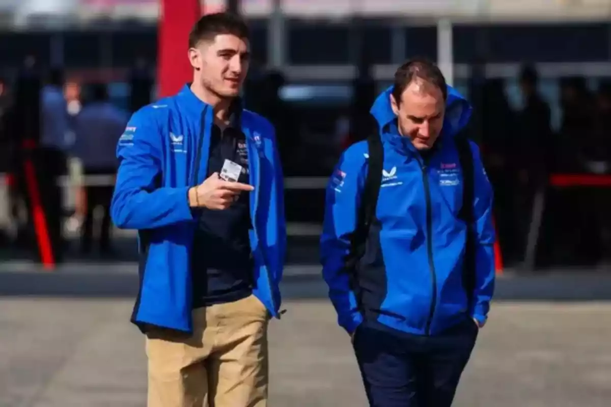 Two people in blue jackets walk outdoors while talking. Two people in blue jackets walk outdoors while talking.
