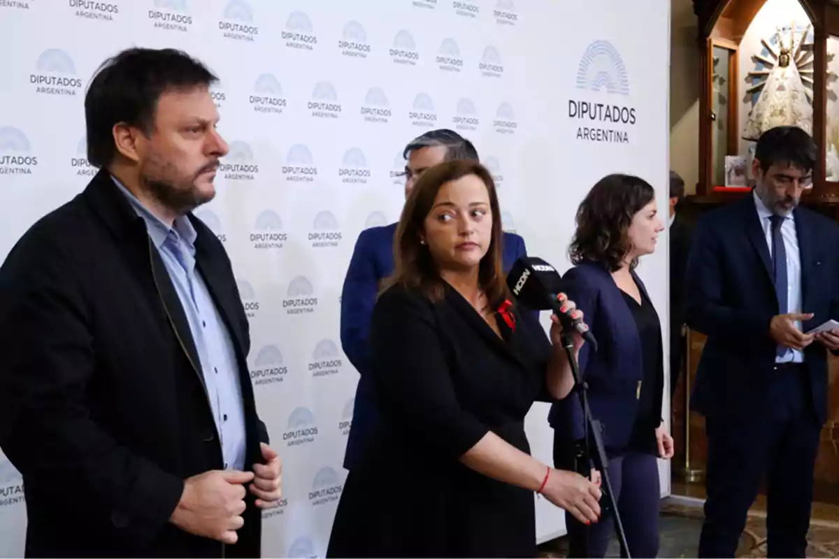 A group of people at a press conference in front of a background that says A group of people at a press conference in front of a background that says