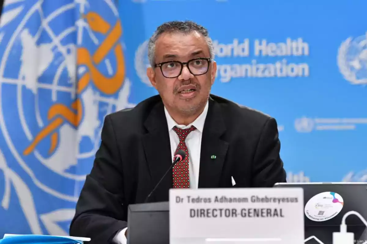 Un hombre con gafas y traje oscuro habla en una conferencia de prensa frente a un fondo azul con el logotipo de la Organización Mundial de la Salud. Un hombre con gafas y traje oscuro habla en una conferencia de prensa frente a un fondo azul con el logotipo de la Organización Mundial de la Salud.
