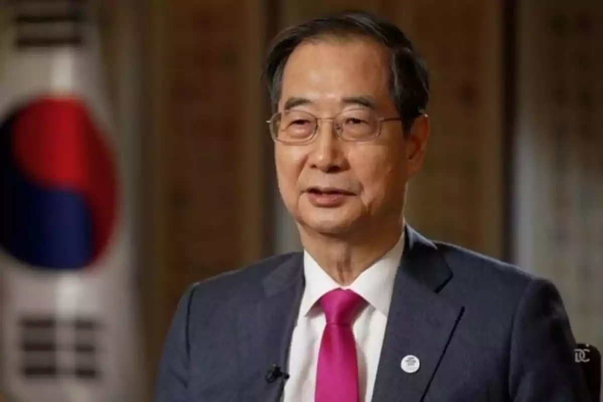 A man with glasses and a pink tie in front of a South Korean flag. A man with glasses and a pink tie in front of a South Korean flag.