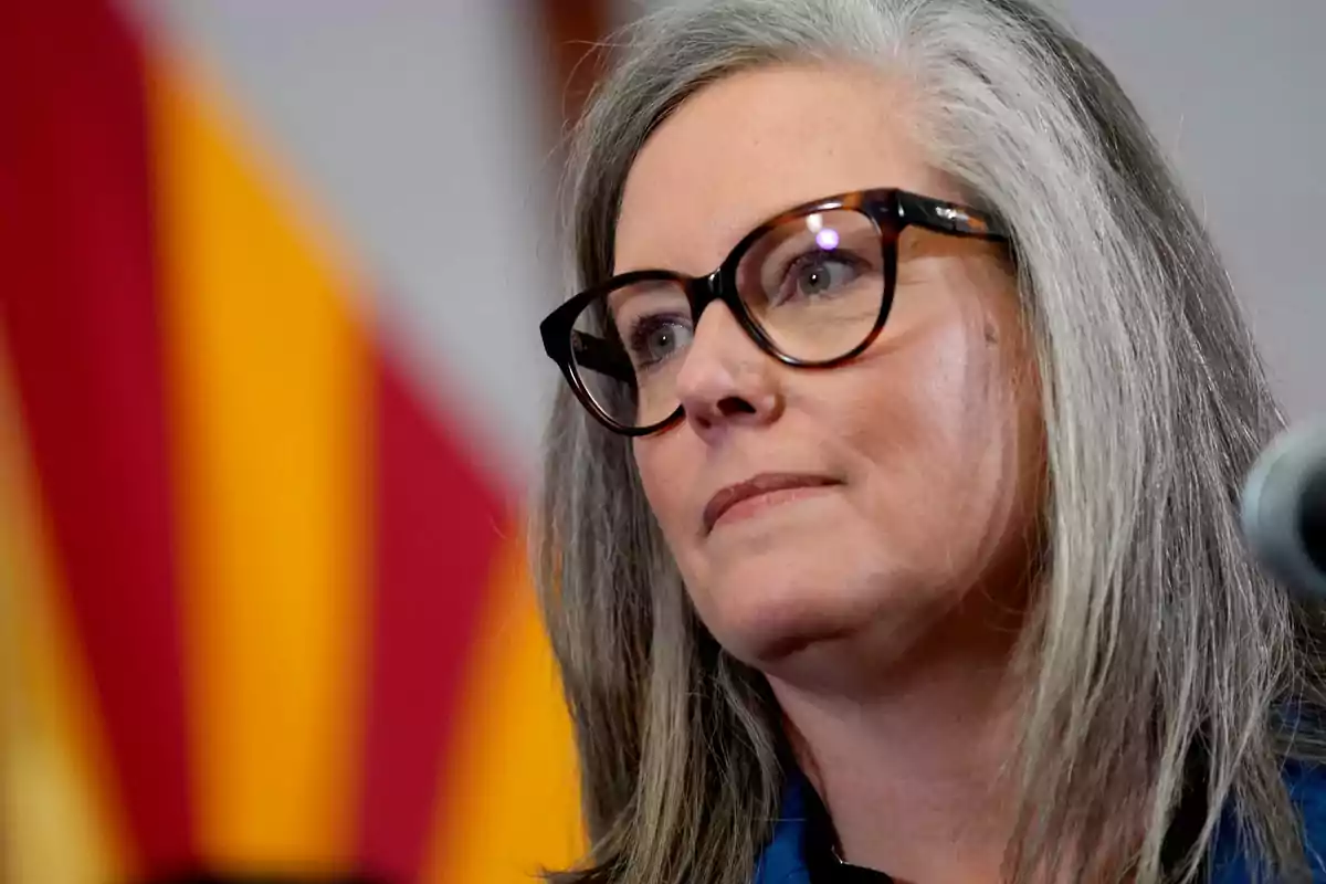 Gray-haired woman with dark glasses looking to the side with a flag in the background Gray-haired woman with dark glasses looking to the side with a flag in the background
