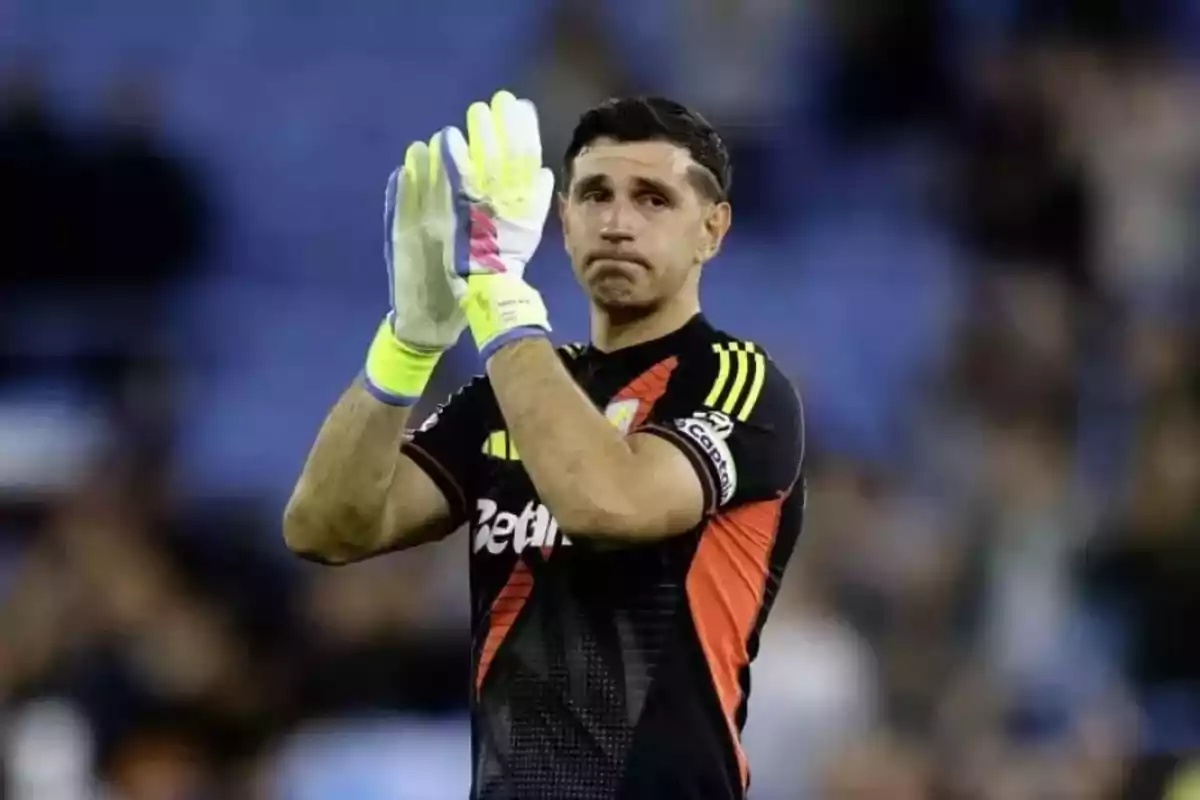 A player with goalkeeper gloves applauds in a stadium. A player with goalkeeper gloves applauds in a stadium.