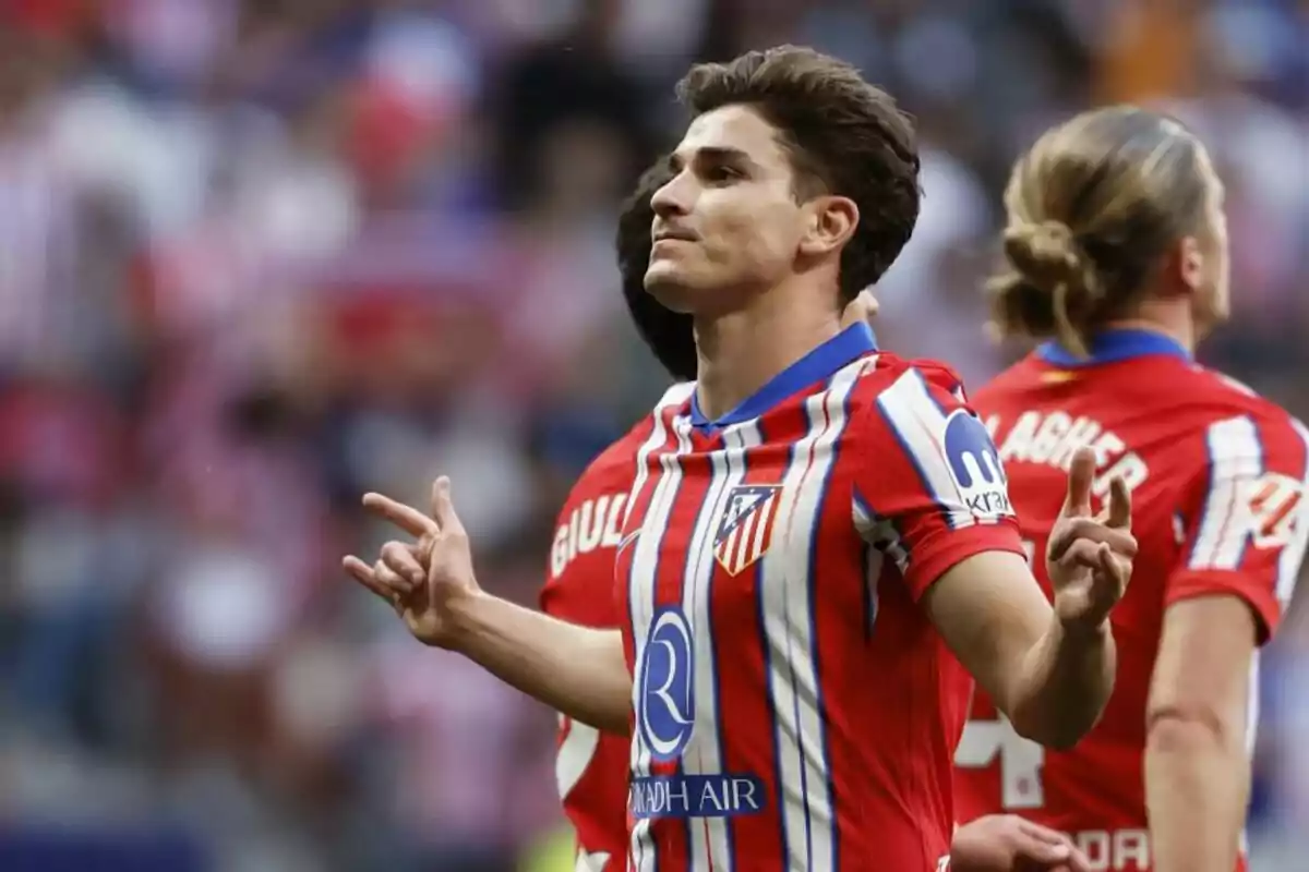 Un jugador de fútbol con uniforme rojo y blanco celebra en el campo.