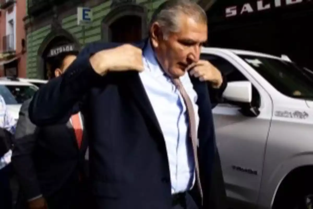 An elderly man puts on a jacket while walking down a street with colorful buildings and a white vehicle parked nearby. An elderly man puts on a jacket while walking down a street with colorful buildings and a white vehicle parked nearby.