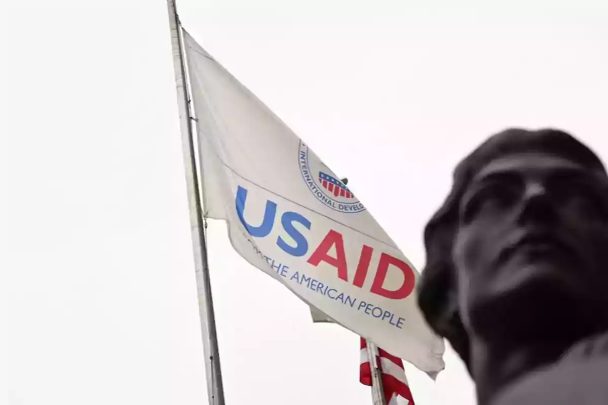 Bandera de USAID ondeando junto a una estatua en primer plano