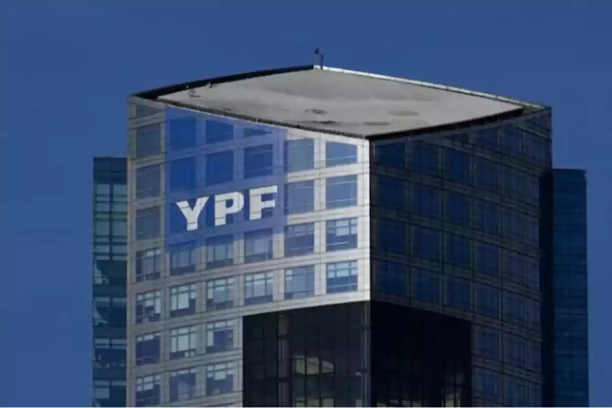 Modern building with a glass facade reflecting the blue sky and large letters on the top. Modern building with a glass facade reflecting the blue sky and large letters on the top.