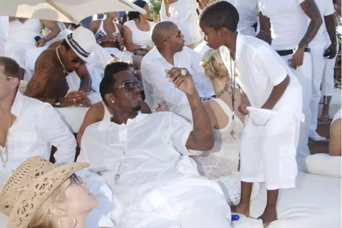 Un grupo de personas vestidas de blanco disfruta de una fiesta al aire libre bajo una sombrilla.