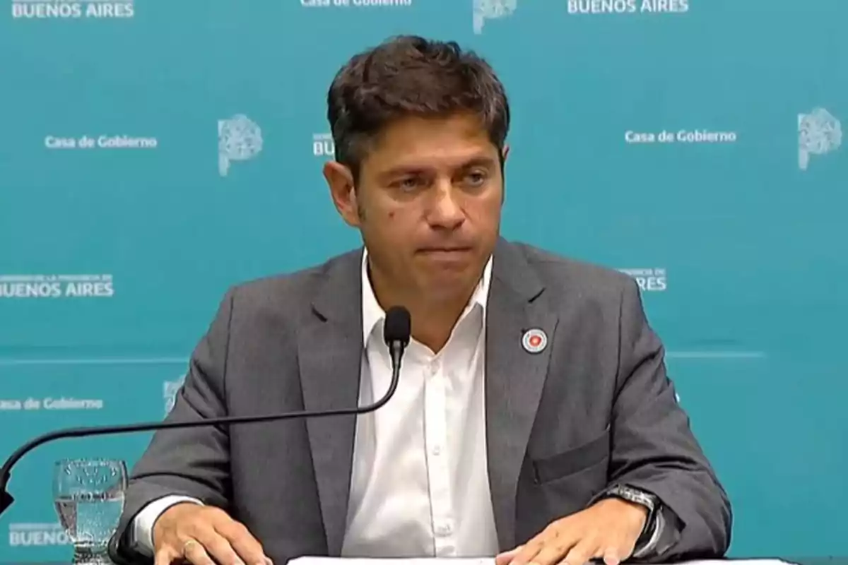 Un hombre en traje gris habla en una conferencia de prensa con un fondo azul que dice "Casa de Gobierno" y "Buenos Aires".