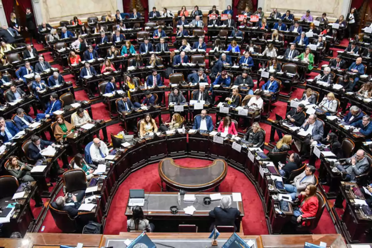 Una asamblea legislativa con numerosos participantes sentados en un hemiciclo discutiendo temas importantes.