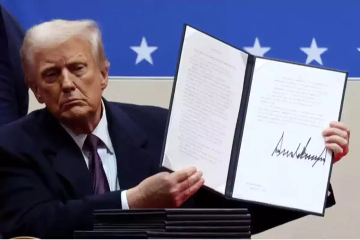 Un hombre de traje sostiene un documento abierto con una firma visible, frente a un fondo azul con estrellas blancas.