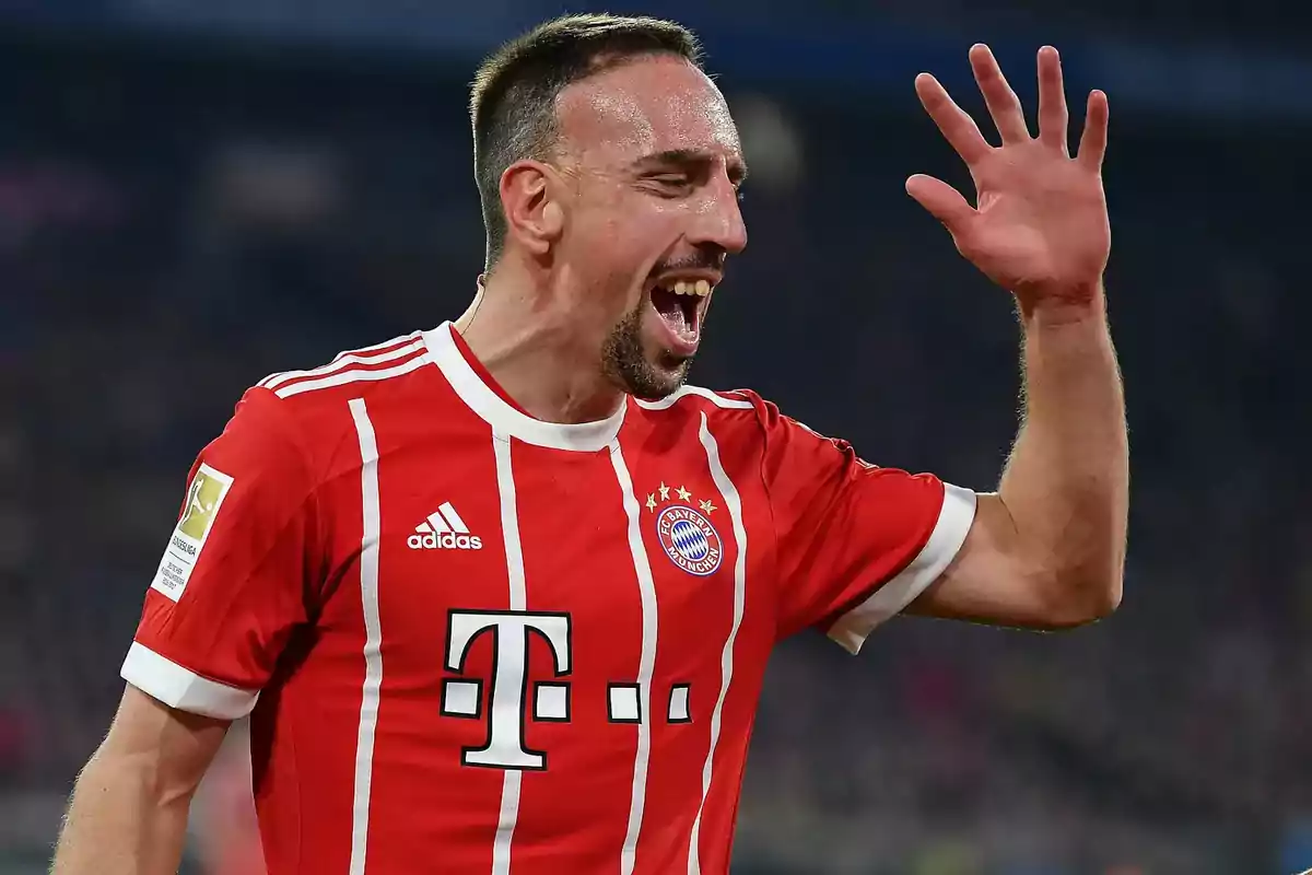 Futbolista con uniforme rojo del Bayern Múnich celebrando en la cancha con la mano levantada y expresión de alegría Futbolista con uniforme rojo del Bayern Múnich celebrando en la cancha con la mano levantada y expresión de alegría
