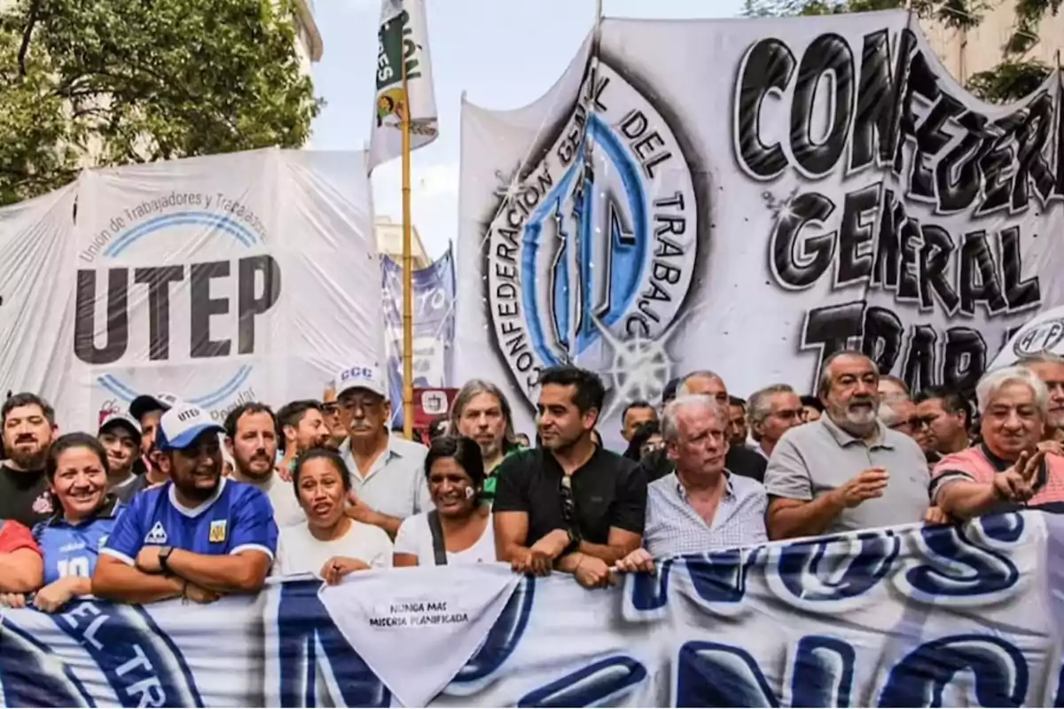 A group of people participates in a demonstration holding banners from the UTEP and the General Confederation of Labor, with flags and signs in an urban setting.