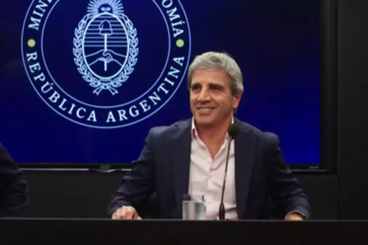 Un hombre sonriente en una conferencia de prensa con el escudo de la República Argentina de fondo.