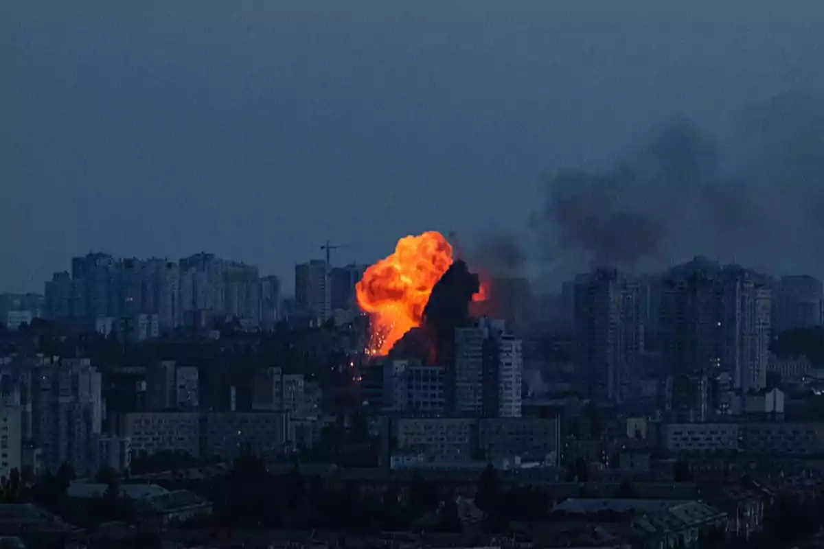 Large-scale explosion in the middle of a city at dusk with smoke and fire between the buildings