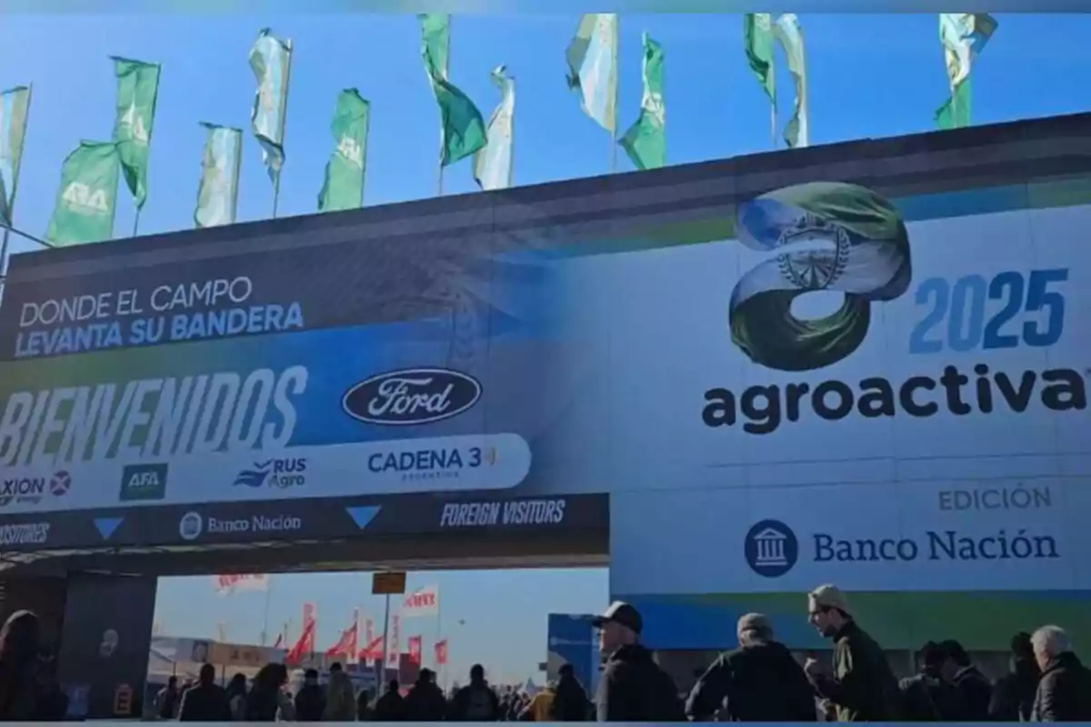 Main entrance of the Agroactiva 2025 exhibition with green flags waving at the top and people entering the event