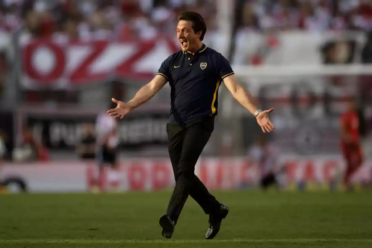 A man in a sports uniform celebrates on a soccer field with open arms and an expression of joy. A man in a sports uniform celebrates on a soccer field with open arms and an expression of joy.