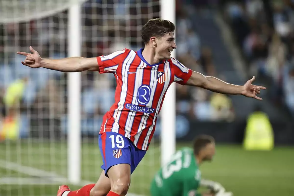 Futbolista del Atlético de Madrid celebrando un gol con los brazos extendidos frente a la portería Futbolista del Atlético de Madrid celebrando un gol con los brazos extendidos frente a la portería