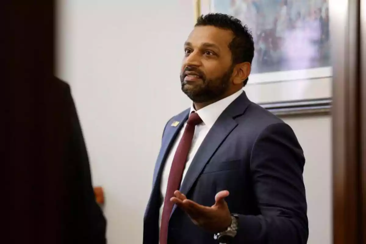 Man with a beard and navy blue suit speaking and gesturing with his hand in an office Man with a beard and navy blue suit speaking and gesturing with his hand in an office