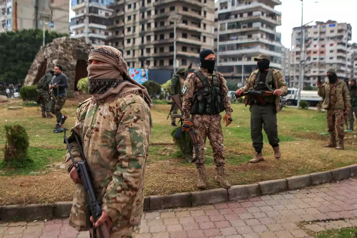 A group of people in camouflage clothing and balaclavas walks through an urban area with tall buildings in the background.