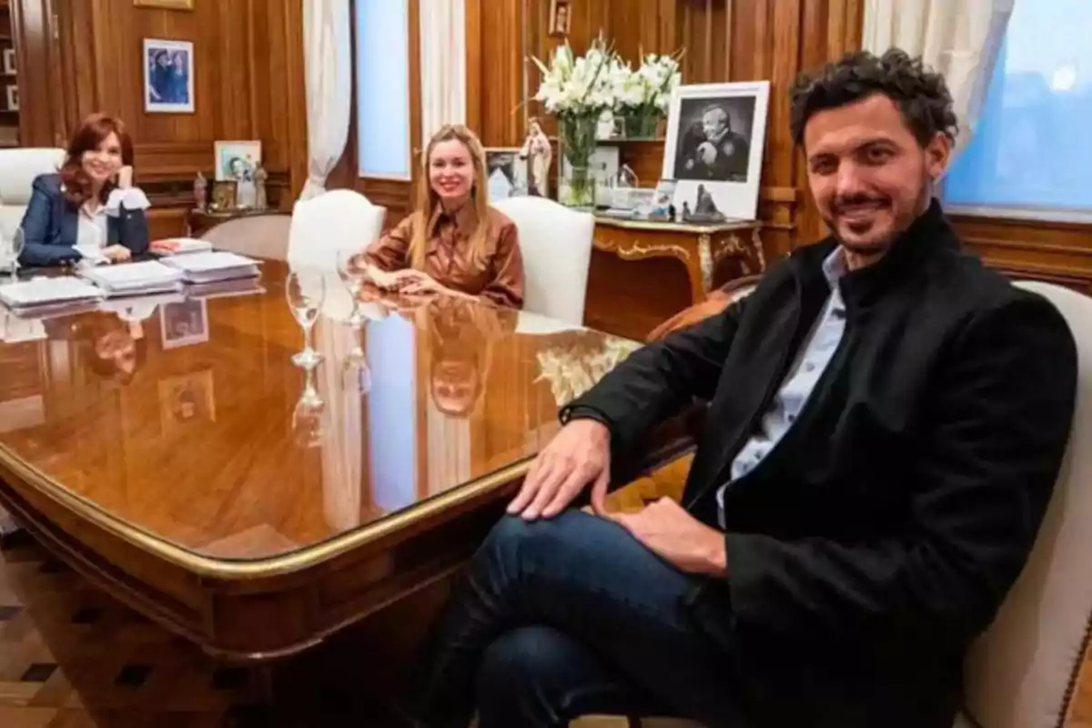 Tres personas sentadas alrededor de una mesa de madera en una oficina elegante con paredes de madera y decoración clásica