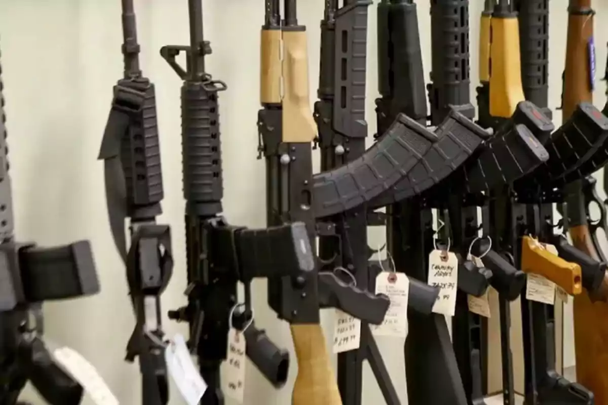 Varios rifles de asalto alineados en exhibición con etiquetas de precio colgando en una tienda de armas Varios rifles de asalto alineados en exhibición con etiquetas de precio colgando en una tienda de armas