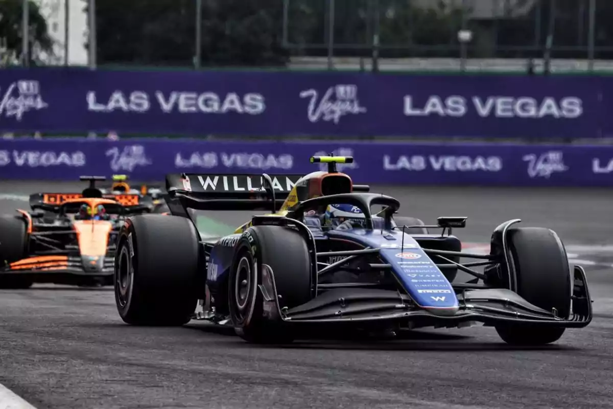 Dos autos de Fórmula 1 compiten en una pista con publicidad de Las Vegas en el fondo.