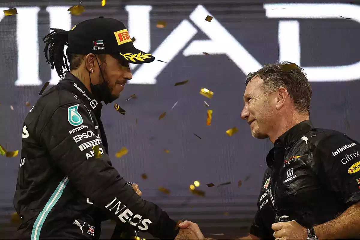 Two men shake hands on a Formula 1 podium as golden confetti falls. Two men shake hands on a Formula 1 podium as golden confetti falls.