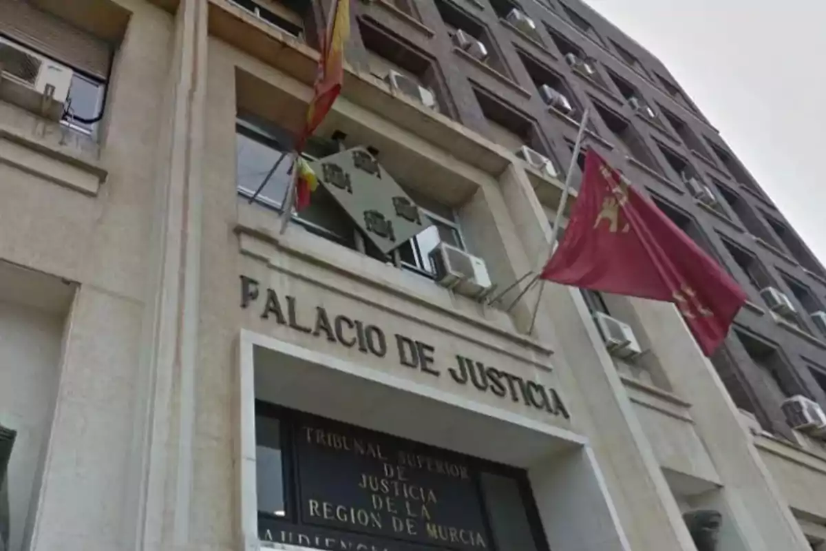 Facade of the Palace of Justice with flags waving and a visible sign at the main entrance