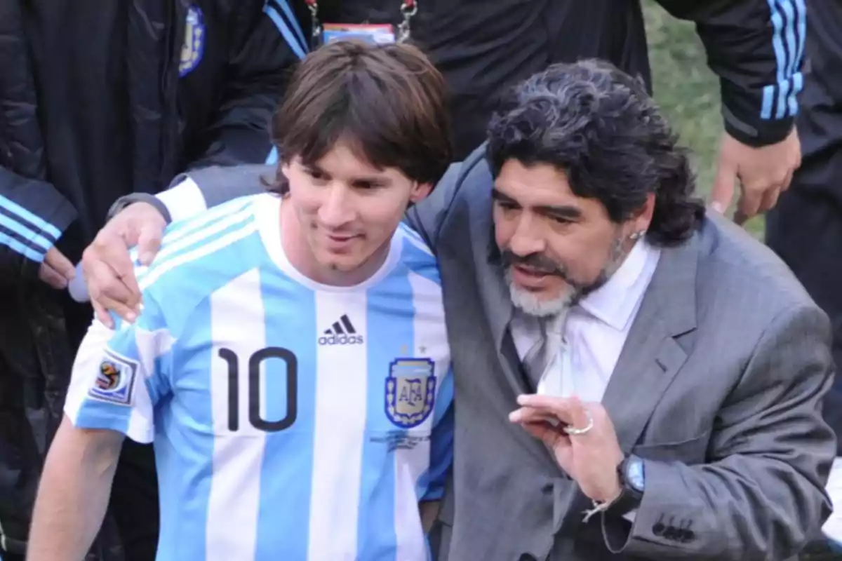 Dos personas posan juntas, una con una camiseta de fútbol de Argentina y la otra con un traje gris. Dos personas posan juntas, una con una camiseta de fútbol de Argentina y la otra con un traje gris.