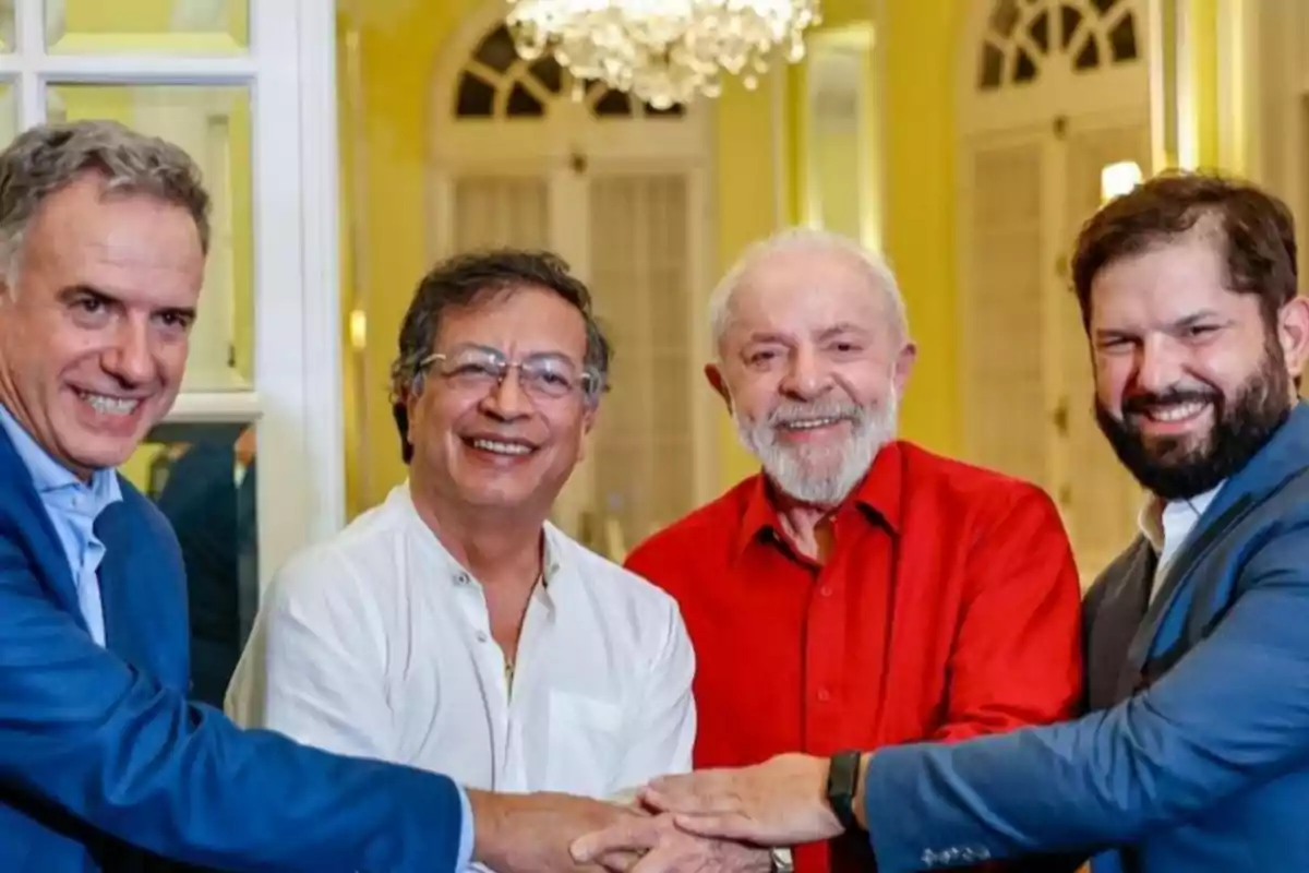 Four smiling men shake hands in an elegant indoor setting.