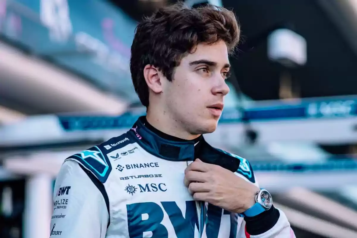 Young motorsport driver in a racing suit adjusting the collar of his uniform in a professional paddock environment Young motorsport driver in a racing suit adjusting the collar of his uniform in a professional paddock environment
