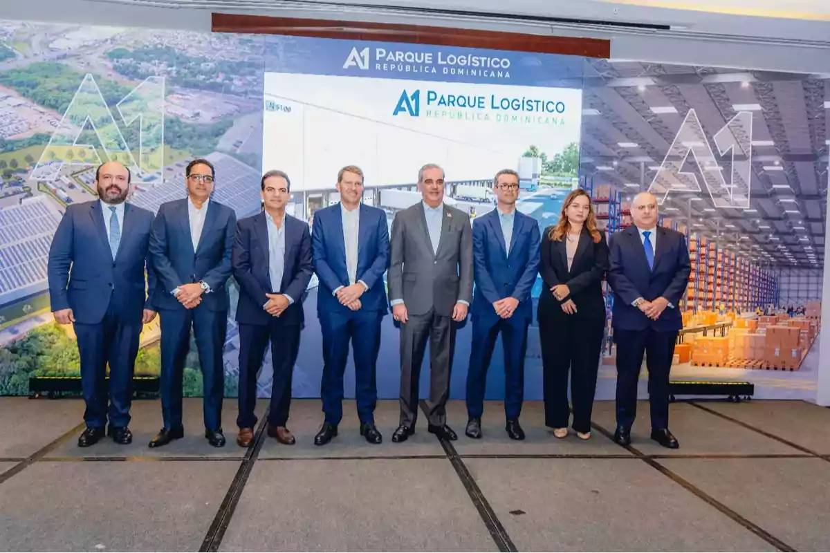 Ocho personas vestidas de traje posan para una foto en un evento corporativo frente a un fondo con imágenes de un parque logístico y el texto A1 Parque Logístico República Dominicana