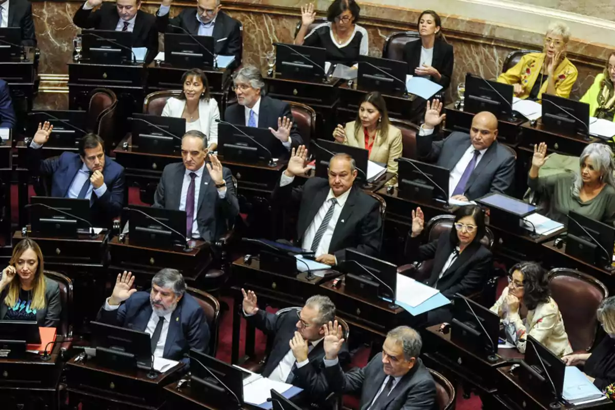 People in a parliamentary chamber raising their hands during a vote