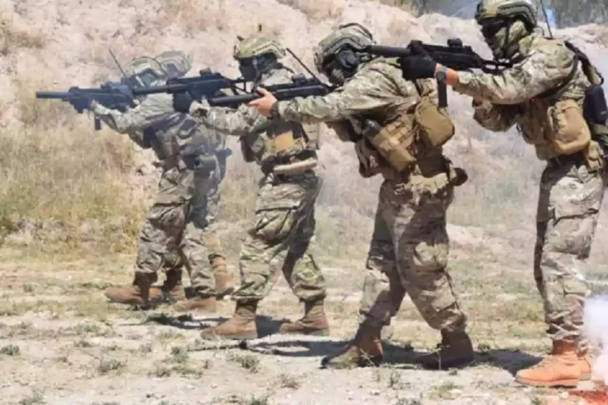 Soldiers in camouflage uniforms advance in formation with weapons in an outdoor setting.