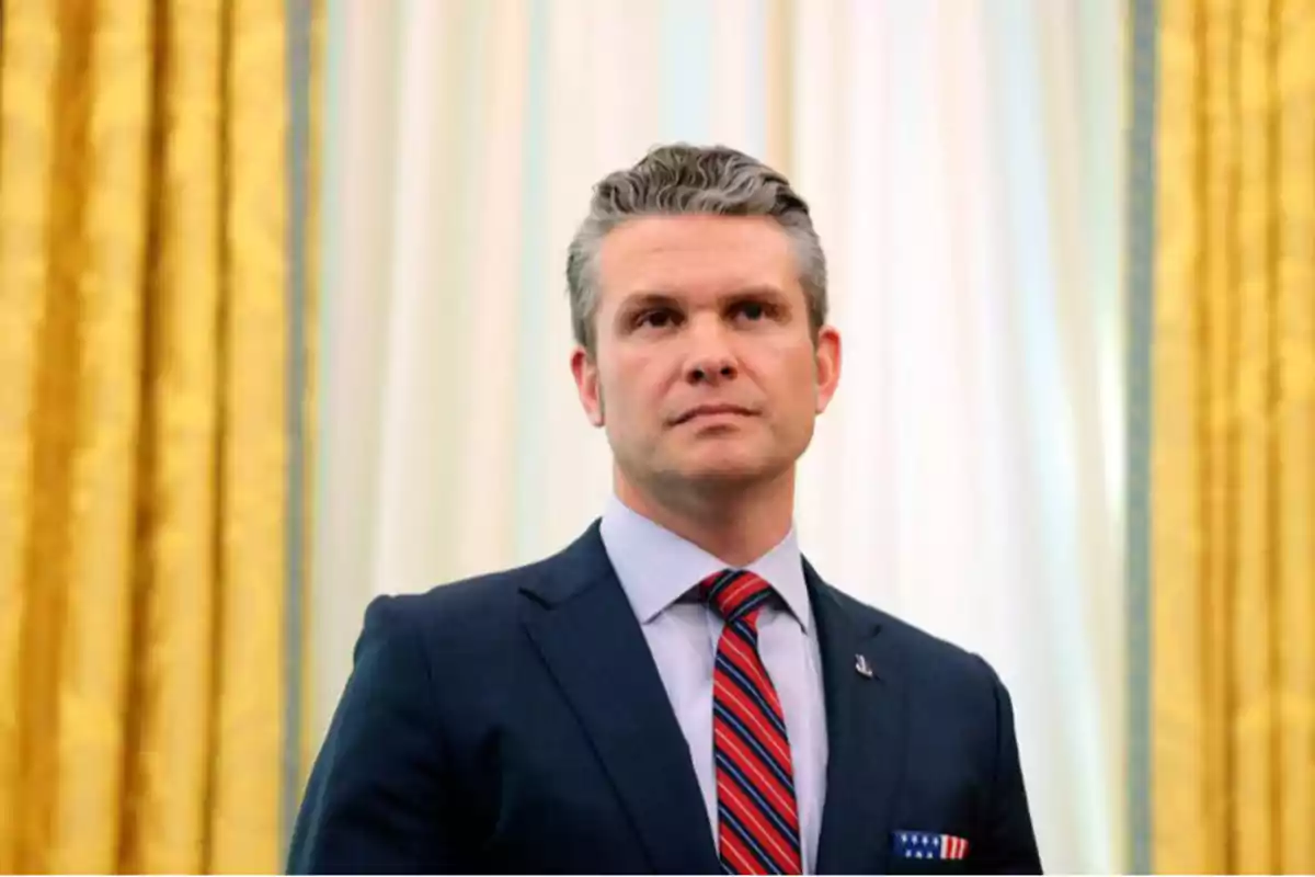 Gray-haired man in a blue suit and red striped tie posing in front of gold and white curtains Gray-haired man in a blue suit and red striped tie posing in front of gold and white curtains