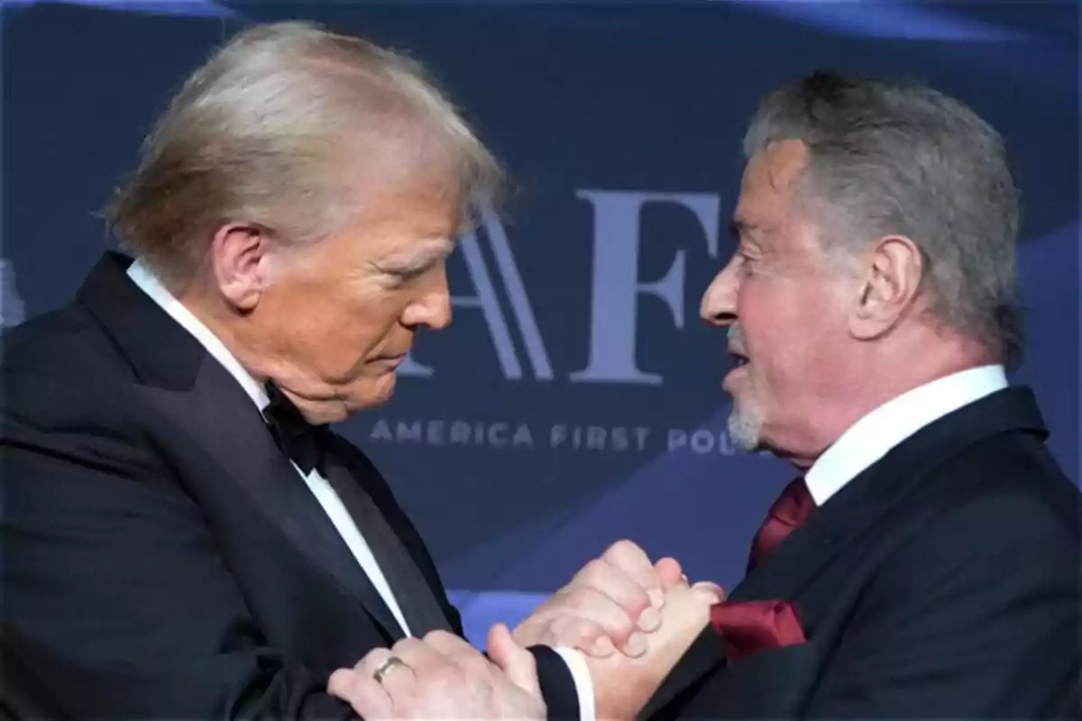 Dos hombres de traje se saludan con un apretón de manos en un evento formal. Dos hombres de traje se saludan con un apretón de manos en un evento formal.
