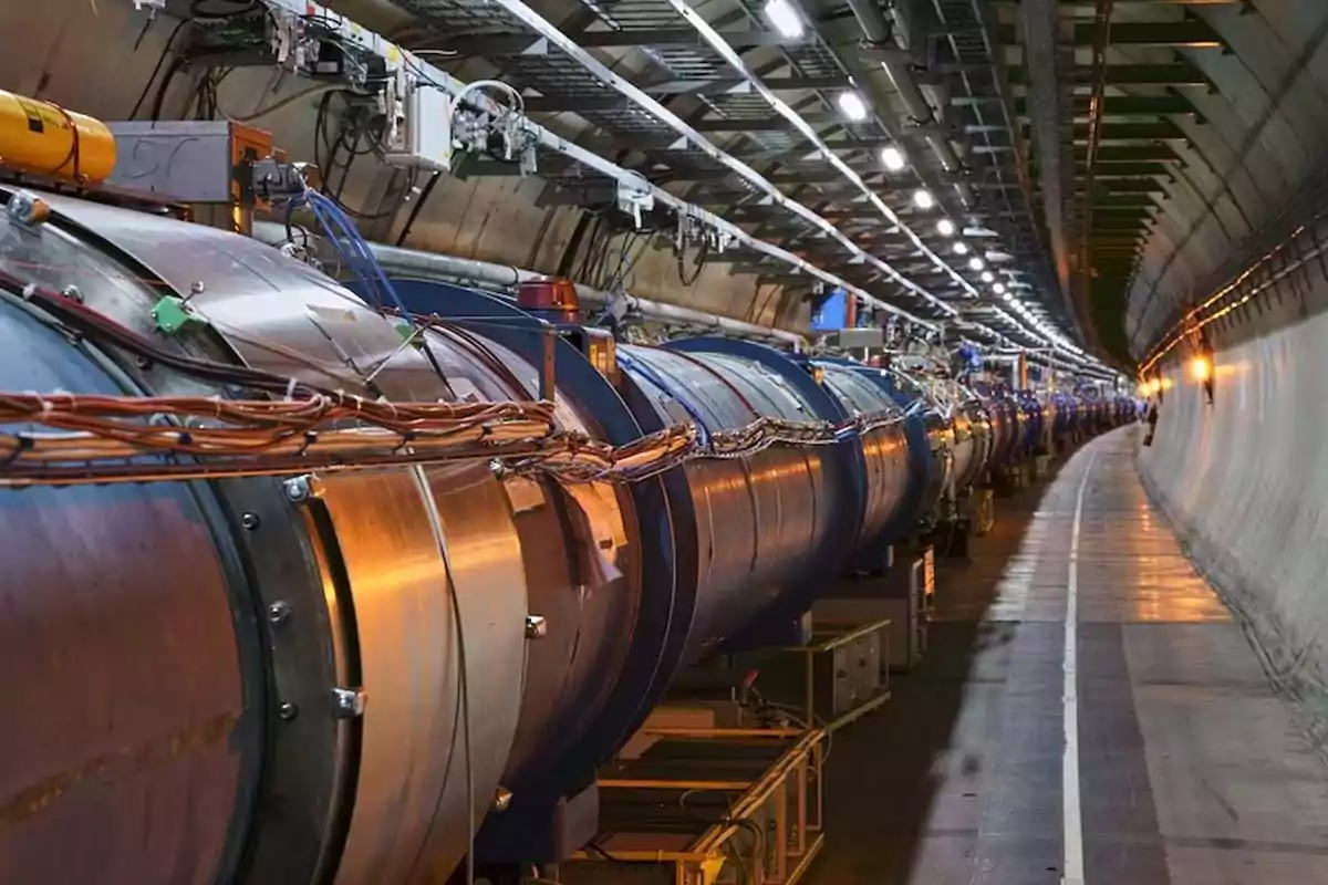 Un túnel subterráneo con un gran acelerador de partículas rodeado de cables y luces. Un túnel subterráneo con un gran acelerador de partículas rodeado de cables y luces.