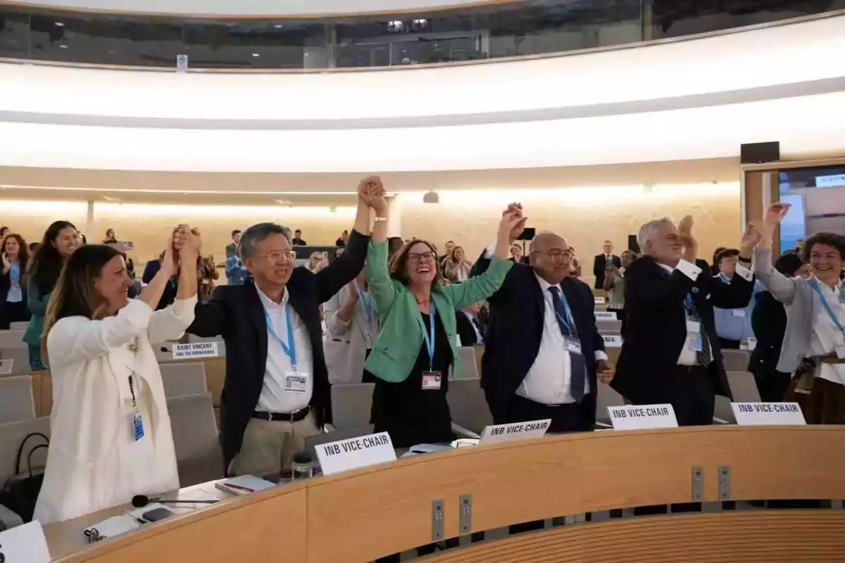 Un grupo de personas en una sala de conferencias levantan las manos en señal de celebración o acuerdo. Un grupo de personas en una sala de conferencias levantan las manos en señal de celebración o acuerdo.