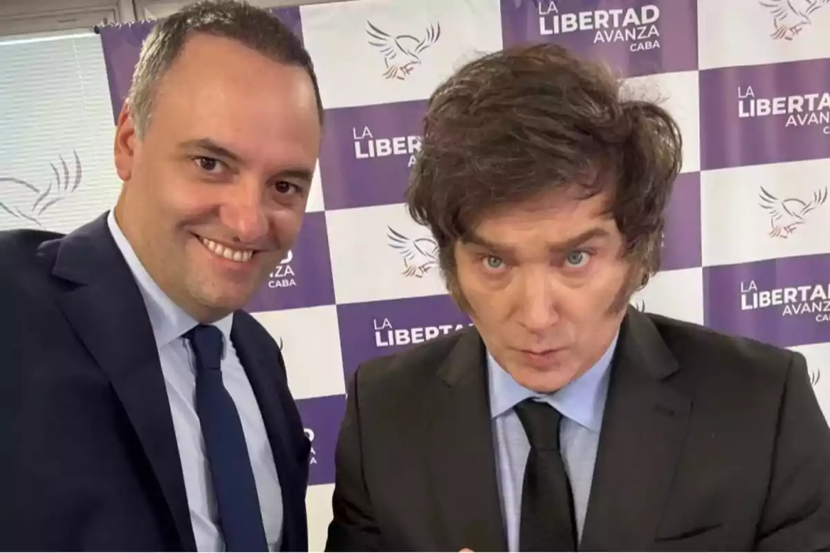 Dos personas posan para una foto frente a un fondo con el logotipo de Dos personas posan para una foto frente a un fondo con el logotipo de