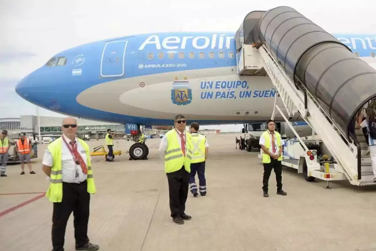 Personal de tierra y un avión de Aerolíneas Argentinas en un aeropuerto.