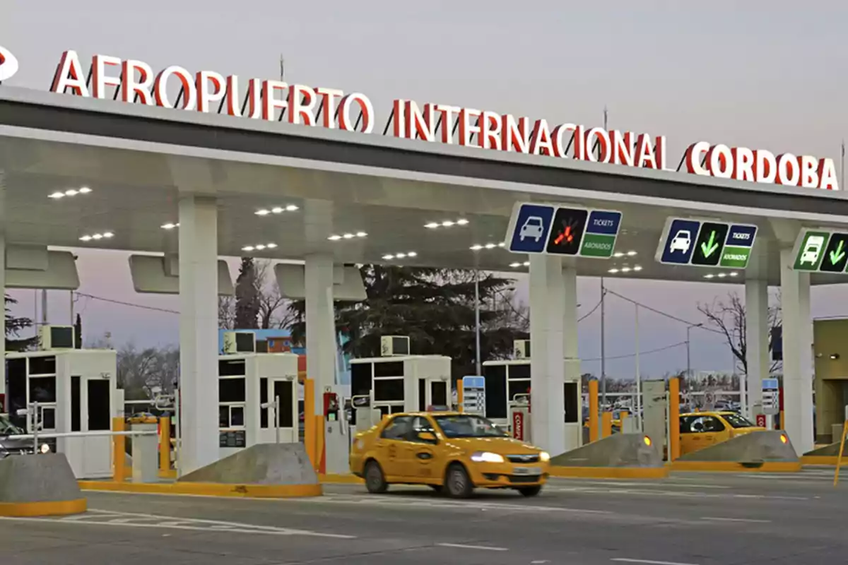 Vehicle entrance to Córdoba International Airport with toll booths and a yellow taxi driving through one of the open lanes