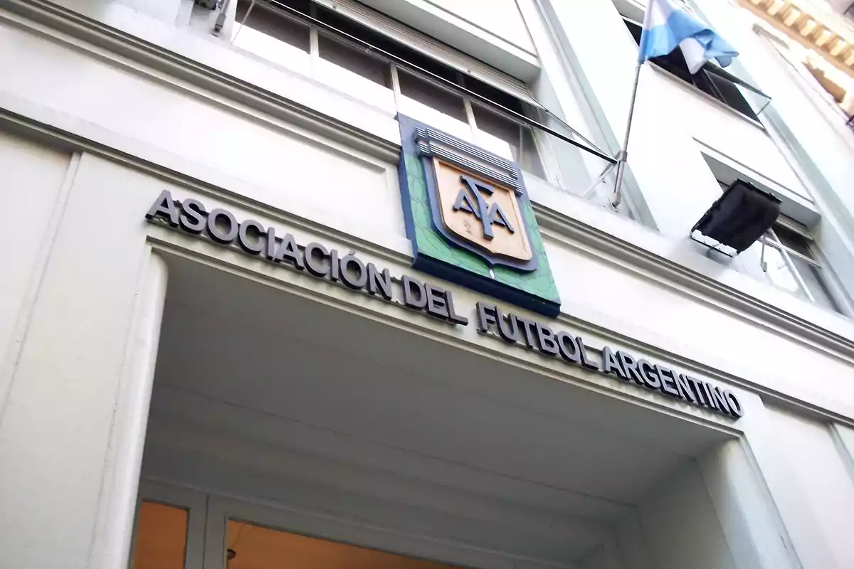 Entrada del edificio de la Asociación del Fútbol Argentino con el escudo de la AFA y una bandera argentina ondeando.