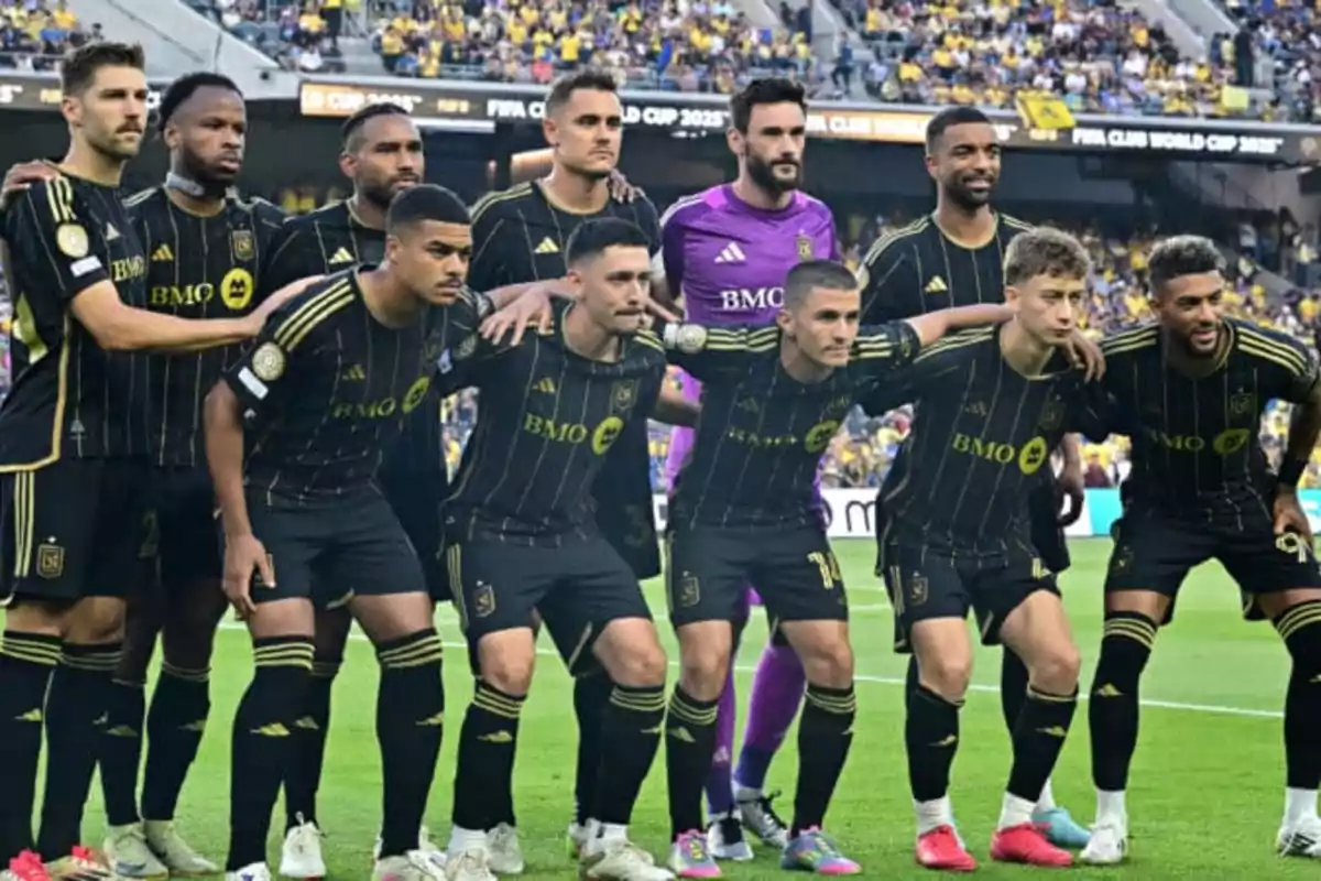 Once jugadores de fútbol posan juntos en el campo antes de iniciar un partido con el estadio lleno de aficionados al fondo