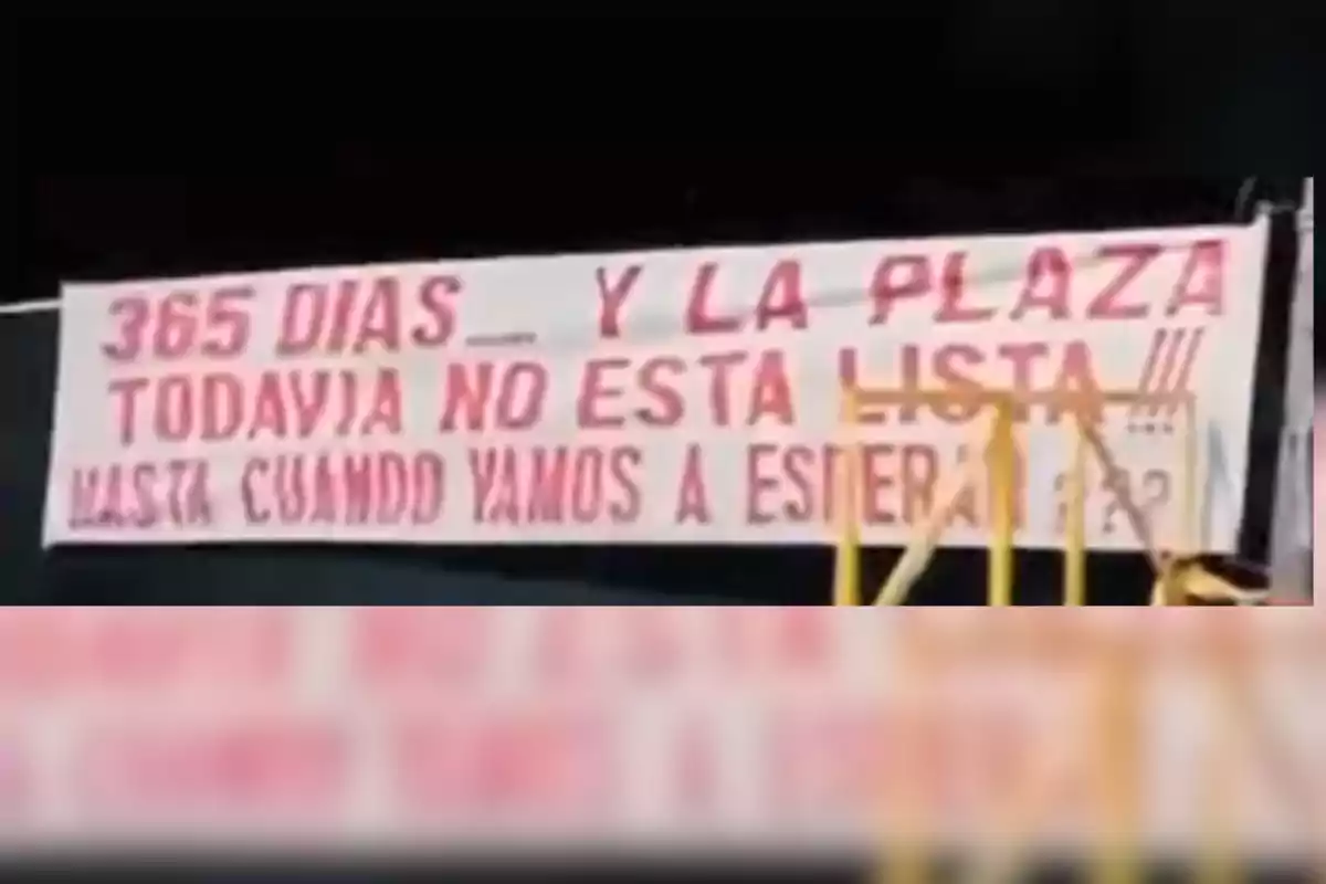White banner with red letters demanding that after 365 days the square is still not finished and asking how much longer they will have to wait.