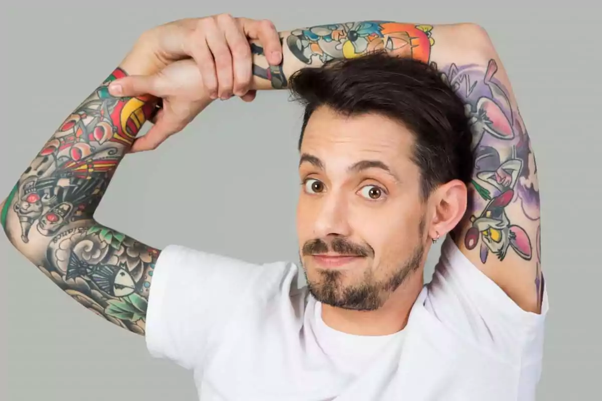 Man with a beard and a white t-jersey showing his tattooed arms while smiling and stretching his arms over his head. Man with a beard and a white t-jersey showing his tattooed arms while smiling and stretching his arms over his head.