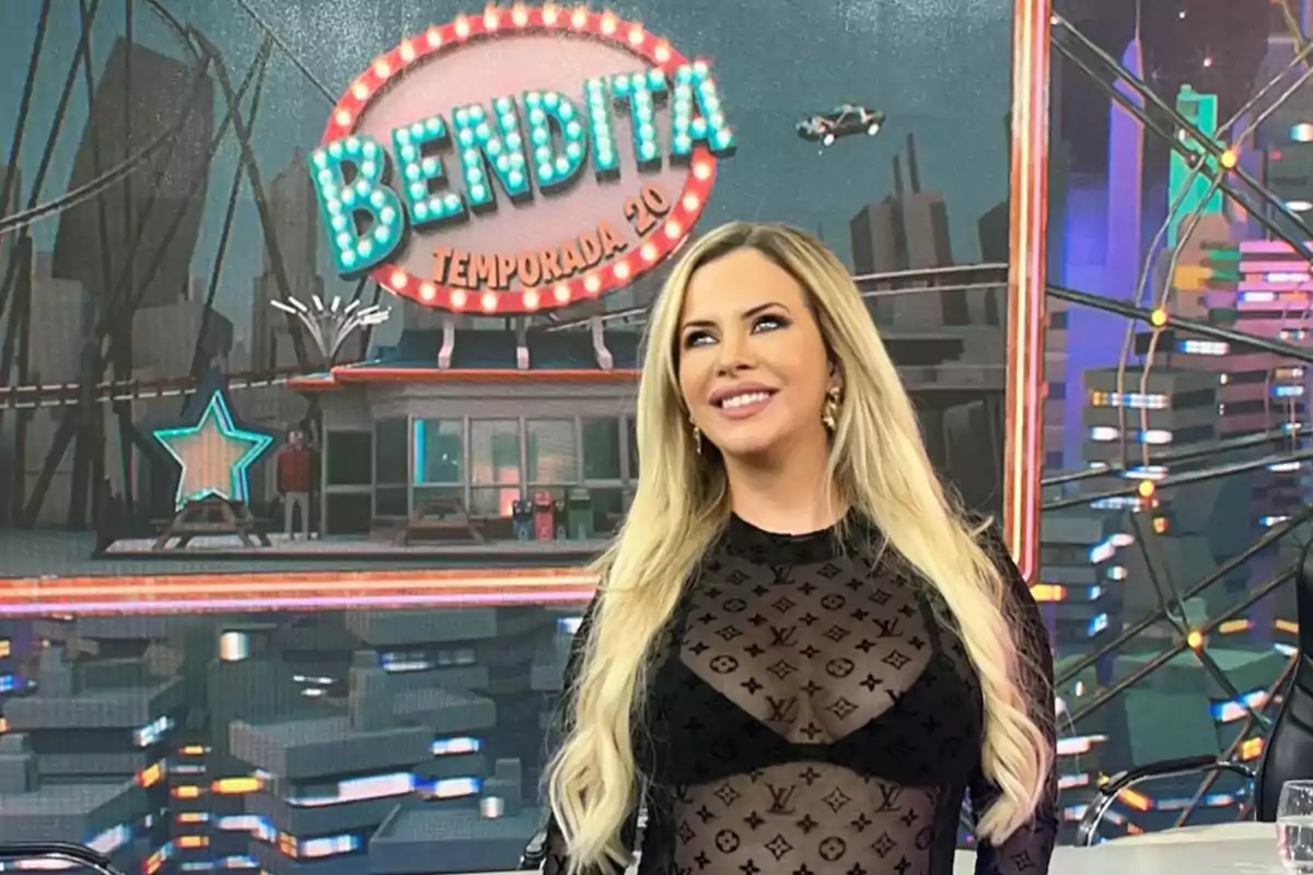 A person with long blonde hair smiles in front of a colorful background with a sign that says "Blessed Season 20."