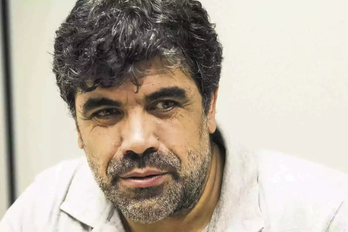 Hombre de cabello rizado y barba con expresión seria mirando hacia un lado